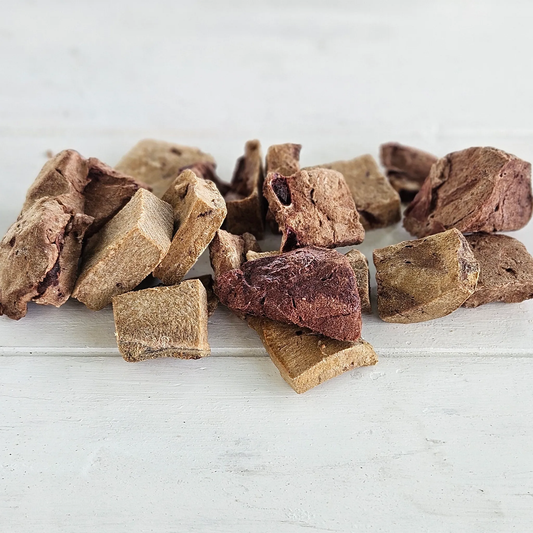 Freeze-dried Bison Medley Tasty Tidbits pieces piled on a white wooden surface