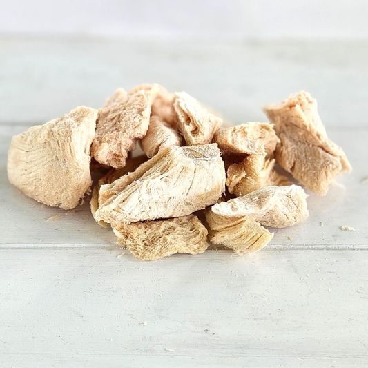 Freeze-dried chicken breast pieces from Chicken Breast Tasty Tidbits on a white wooden surface